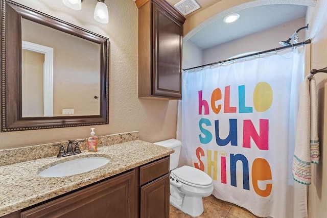 bathroom with toilet, vanity, curtained shower, tile patterned flooring, and a textured wall