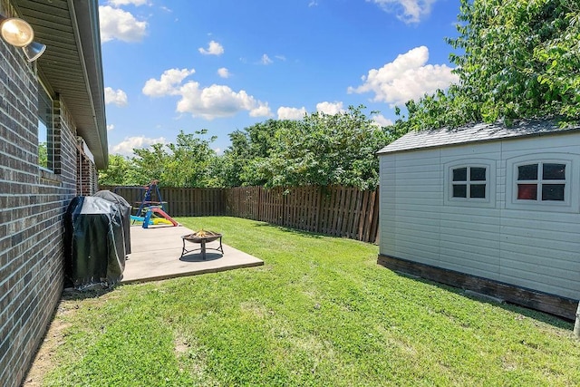 view of yard featuring a fire pit, an outbuilding, a shed, and a patio area