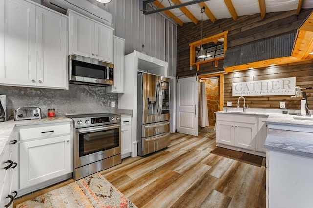 103 County Road 1522, Eureka Springs, AR 72632 - kitchen with appliances with stainless steel finishes, high vaulted ceiling, wooden walls, white cabinetry, and decorative backsplash