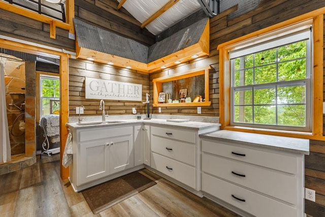 103 County Road 1522, Eureka Springs, AR 72632 - kitchen with wooden walls, white cabinetry, wood finished floors, light stone countertops, and custom exhaust hood