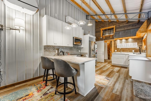 103 County Road 1522, Eureka Springs, AR 72632 - kitchen with appliances with stainless steel finishes, high vaulted ceiling, white cabinetry, wooden walls, and a peninsula