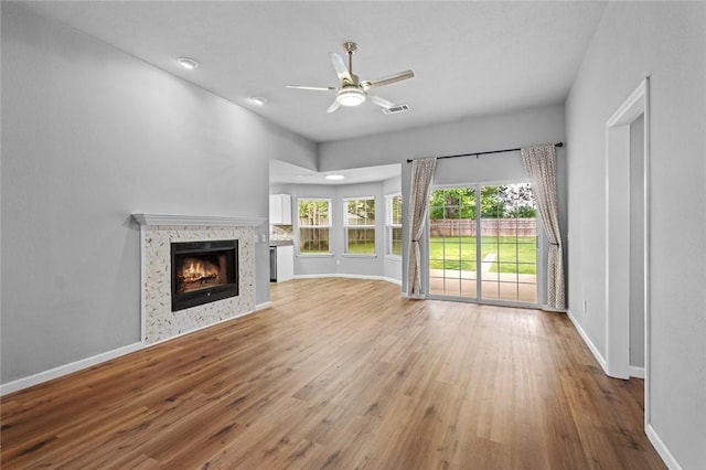 unfurnished living room with wood finished floors, a fireplace, a ceiling fan, and baseboards