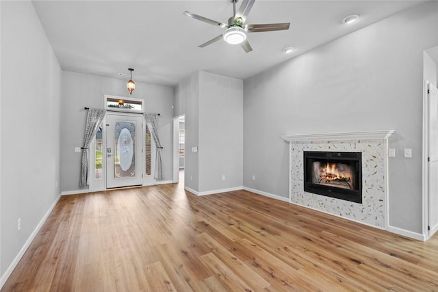 foyer with wood finished floors, a fireplace, a ceiling fan, and baseboards