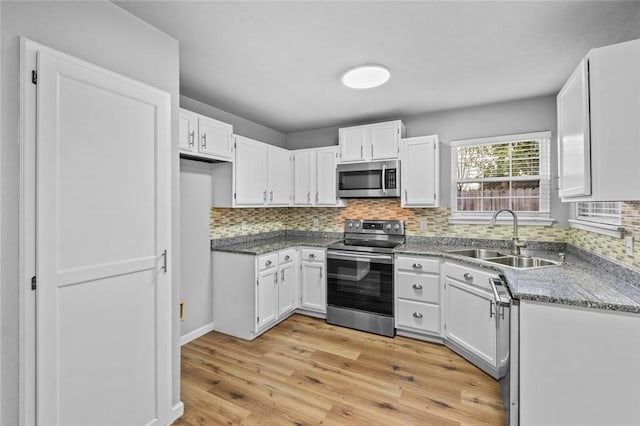 kitchen with stainless steel appliances, a sink, white cabinetry, and backsplash