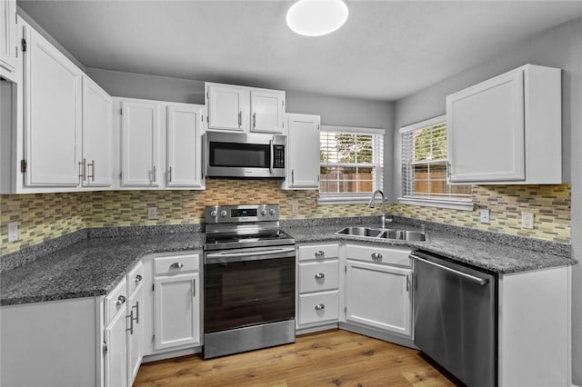 kitchen with appliances with stainless steel finishes, a sink, white cabinets, and decorative backsplash