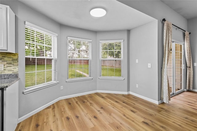 unfurnished dining area with baseboards and light wood-type flooring