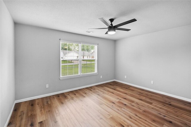 empty room featuring wood finished floors, ceiling fan, and baseboards