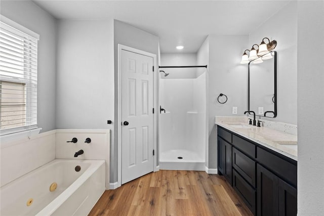 bathroom with wood finished floors, a whirlpool tub, a stall shower, and double vanity