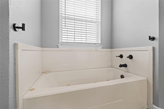 full bathroom with a textured wall and a garden tub