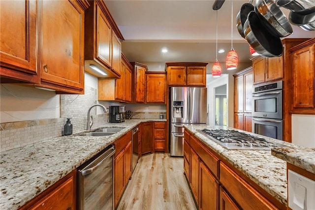 9696 Fuller Rd, Rogers, AR 72756 - kitchen with appliances with stainless steel finishes, light wood-type flooring, a sink, light stone countertops, and decorative backsplash