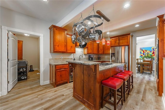 9696 Fuller Rd, Rogers, AR 72756 - kitchen with stainless steel fridge with ice dispenser, light wood-type flooring, brown cabinetry, a kitchen bar, and baseboards