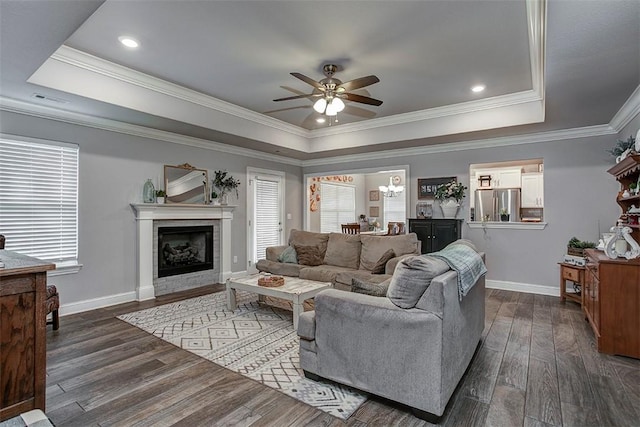 living room with a tray ceiling, ceiling fan, plenty of natural light, crown molding, and recessed lighting