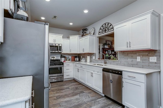 kitchen with stainless steel appliances, a sink, white cabinets, tasteful backsplash, and recessed lighting