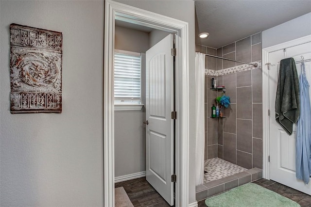 bathroom featuring tiled shower, baseboards, and wood finished floors