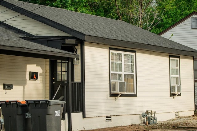 view of side of property featuring crawl space, a shingled roof, and cooling unit