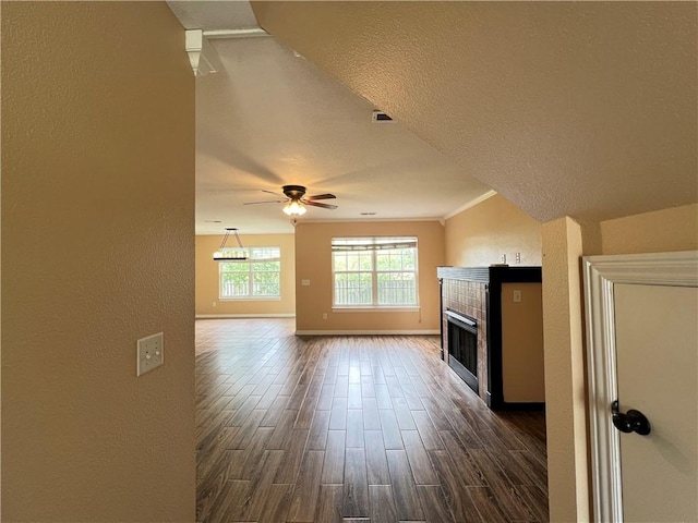 3703 Hansom Loop, Bentonville, AR 72712 - unfurnished living room featuring a tile fireplace, dark wood-style flooring, baseboards, a textured wall, and a ceiling fan