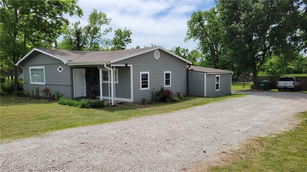 view of front facade with dirt driveway and a front yard