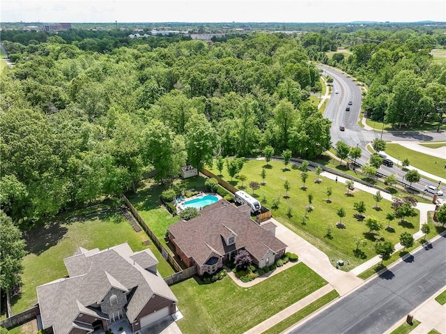 drone / aerial view of a heavily wooded area and a pool area