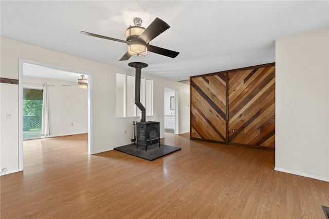 170 NC-8376, Jasper, AR 72641 - unfurnished living room featuring a ceiling fan, a wood stove, wood finished floors, and baseboards