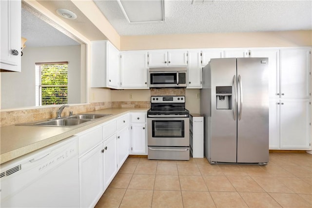 kitchen with stainless steel appliances, a sink, white cabinetry, light countertops, and a textured ceiling