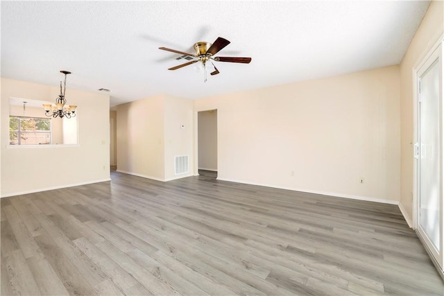 unfurnished living room with a chandelier, wood finished floors, ceiling fan, and baseboards