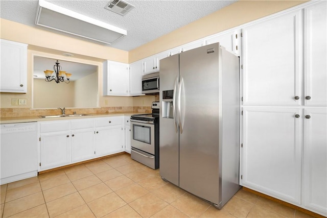 kitchen featuring stainless steel appliances, a sink, white cabinets, light countertops, and a textured ceiling