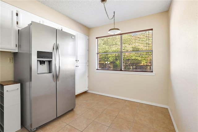 kitchen with stainless steel refrigerator with ice dispenser, baseboards, white cabinets, light tile patterned flooring, and pendant lighting