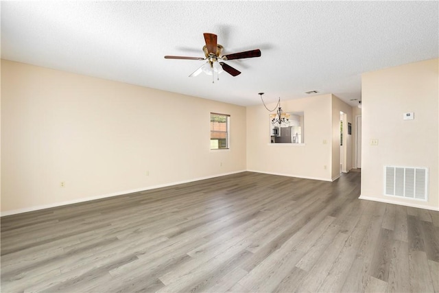 unfurnished room with ceiling fan, wood finished floors, baseboards, a chandelier, and a textured ceiling