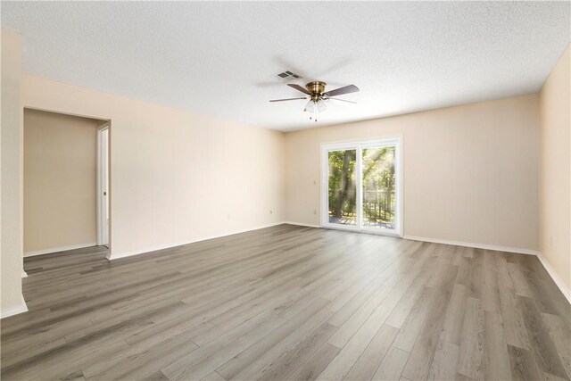 spare room with a ceiling fan, wood finished floors, baseboards, and a textured ceiling