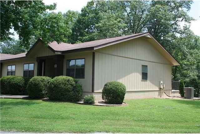 view of side of property featuring a lawn and cooling unit