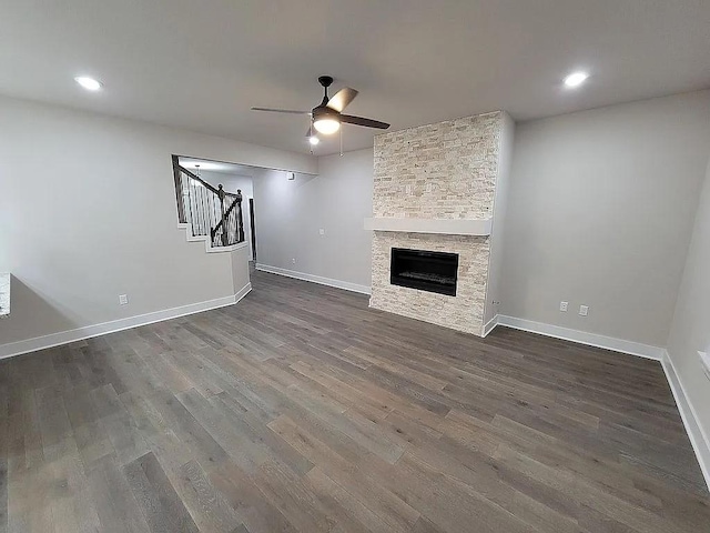 4202 SW Plumley Ave, Bentonville, AR 72713 - unfurnished living room featuring a ceiling fan, dark wood-style flooring, stairs, baseboards, and a fireplace
