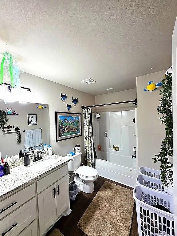 4202 SW Plumley Ave, Bentonville, AR 72713 - full bathroom featuring wood finished floors, shower / bath combo with shower curtain, toilet, vanity, and a textured ceiling