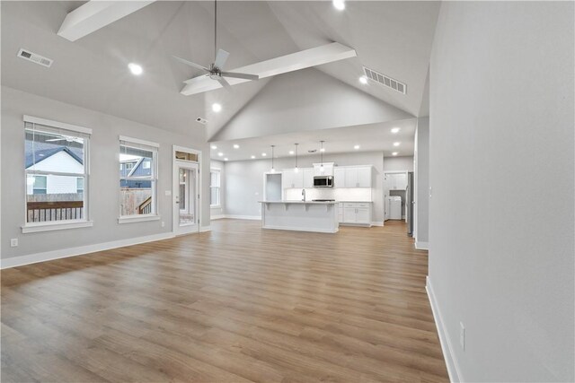 unfurnished living room featuring recessed lighting, high vaulted ceiling, light wood-style floors, baseboards, and ceiling fan