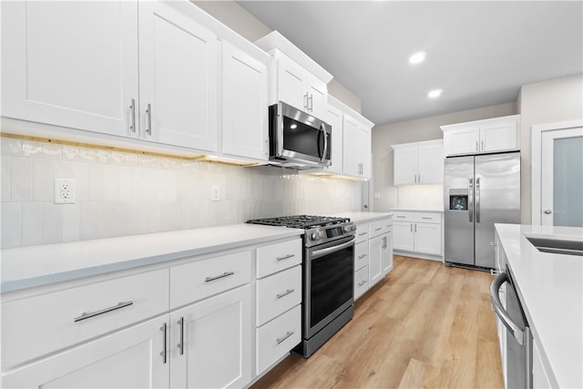 kitchen with stainless steel appliances, tasteful backsplash, white cabinetry, light countertops, and recessed lighting