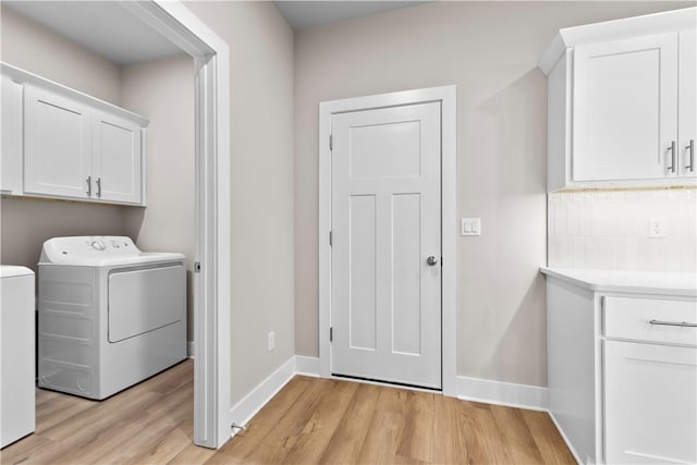 washroom featuring light wood-type flooring, baseboards, washing machine and clothes dryer, and cabinet space