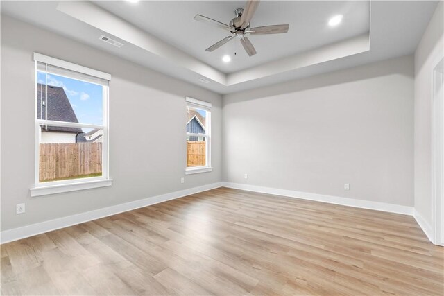 spare room with a raised ceiling, light wood-style flooring, ceiling fan, baseboards, and recessed lighting