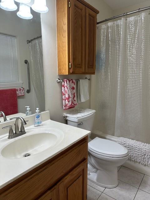 bathroom featuring tile patterned flooring, toilet, vanity, and shower / tub combo with curtain