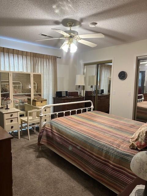 bedroom featuring a textured ceiling, carpet floors, ceiling fan, and a closet