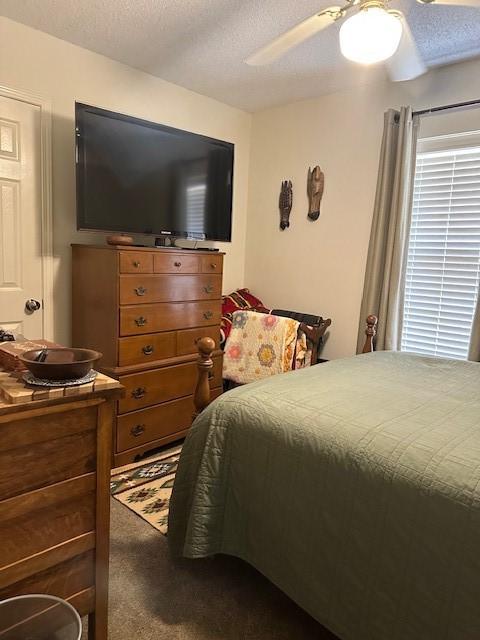 bedroom with dark carpet, a textured ceiling, and ceiling fan