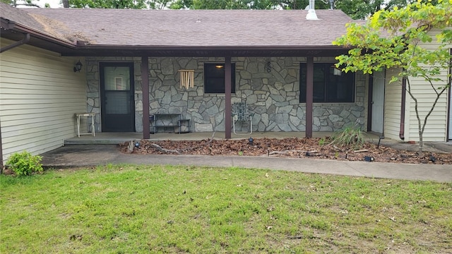 property entrance featuring a porch, stone siding, a lawn, and roof with shingles