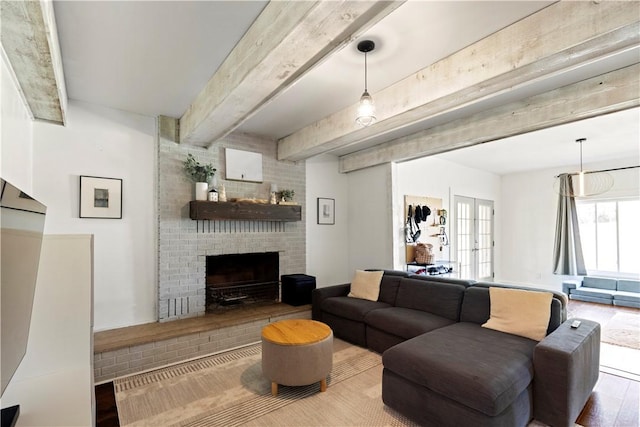 living room with a brick fireplace, beamed ceiling, and wood finished floors