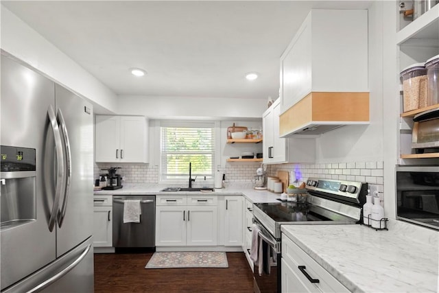 kitchen with appliances with stainless steel finishes, a sink, open shelves, dark wood-style floors, and white cabinetry