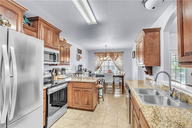 kitchen with appliances with stainless steel finishes, a sink, light countertops, a peninsula, and a chandelier