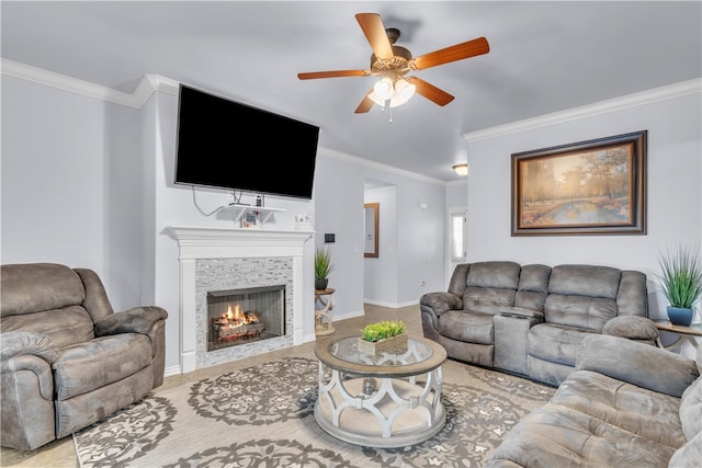 living room with a ceiling fan, ornamental molding, a fireplace, and baseboards