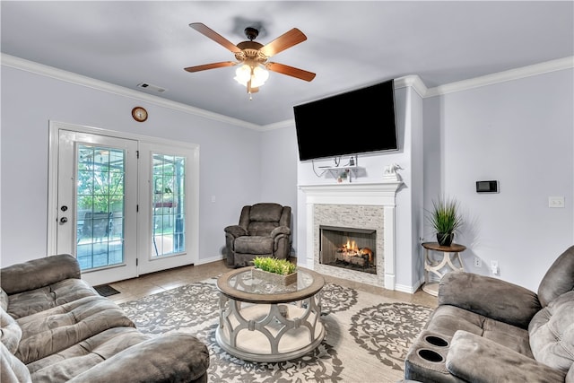 living area with a tile fireplace, crown molding, a ceiling fan, light tile patterned flooring, and baseboards