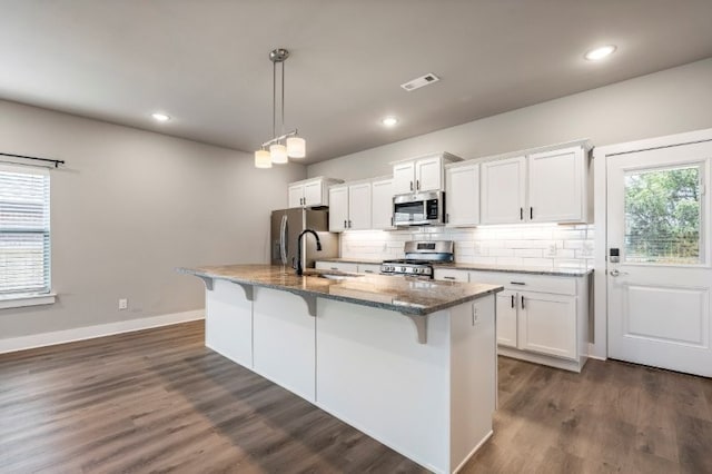 4400 SW Pawhuska St, Bentonville, AR 72713 - kitchen featuring appliances with stainless steel finishes, a sink, a kitchen breakfast bar, an island with sink, and dark stone counters