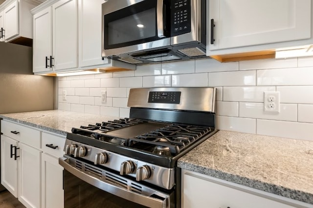 4400 SW Pawhuska St, Bentonville, AR 72713 - kitchen featuring stainless steel appliances, white cabinets, light stone countertops, decorative backsplash, and dark wood-style floors