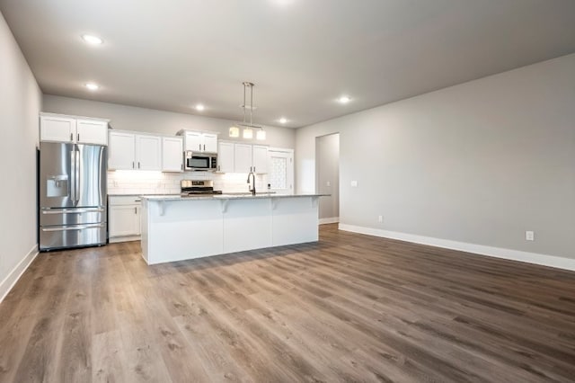 4400 SW Pawhuska St, Bentonville, AR 72713 - kitchen with appliances with stainless steel finishes, baseboards, white cabinets, a center island with sink, and recessed lighting
