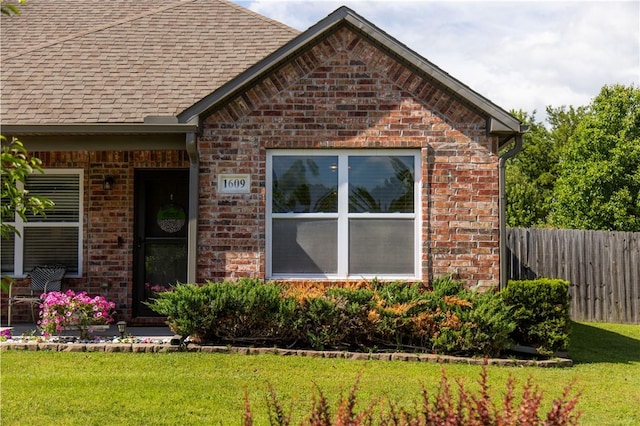 view of front of home featuring brick siding and a shingled roof