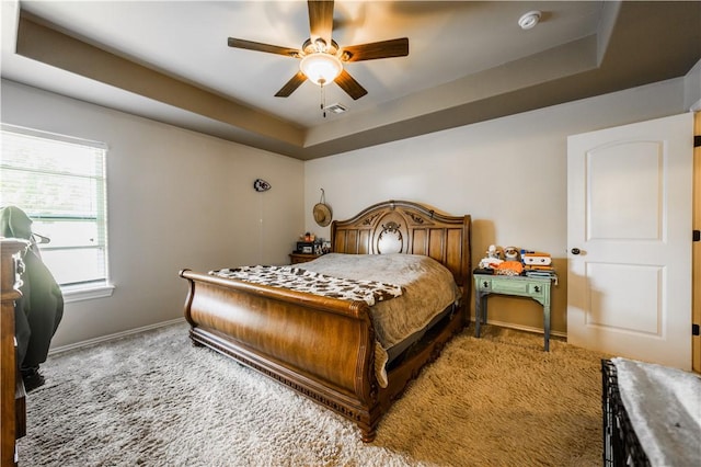 bedroom with carpet, a raised ceiling, baseboards, and a ceiling fan